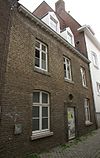 Huis met lijstgevel, voorzien van een geprofileerde ingangsomlijsting van Naamse steen, met oreillons.