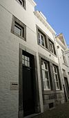 Voorhuis. Achterbouw haaks hierop met hardstenen kozijnen en horizontale reliefbanden.