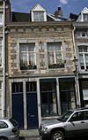 Huis, waarvan de voorgevel, eindigt in een hoofdgestel met gegroefde consoles.