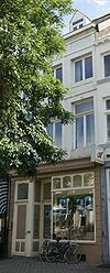 Huis met gepleisterde lijstgevel, voorzien van segmentboogvensters en een uitgebouwde erker op de verdieping.
