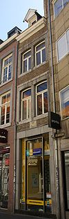 Huis met smalle lijstgevel, voorzien van gekoppelde lateiboogvensters in Naamse steen en een gevelsteen met borstbeeld van een man 1754.
