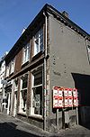 Hoekhuis, waarvan de gevels eindigen in een Maaslands hoofdgestel met consoles.