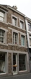 Huis met lijstgevel, met horizontale reliefbanden en segmentboogvensters in Naamse steen.