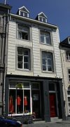 Huis met lijstgevel van Naamse steen, met segmentboogvensters tussen brede geblokte dammen.