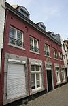 Huis met brede lijstgevel, beneden met hardstenen kozijnen waaruit de kruisen verdwenen zijn.