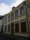 Huis met brede gepleisterde lijstgevel en koetspoort.