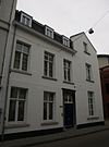 Huis, onder een haaks op de straat gericht zadeldak. Zijgevel in de trant der zgn. Maaslandse renaissance eindigend in een hoofdgestel met consoles.