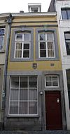 Huis met lijstgevel, van mergel met vensters in uitspringende segmentboogomlijstingen onder een bij de sluitstenen omgekorniste profiellijst.
