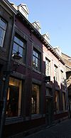 Hoekhuis met brede lijstgevel met een gevelsteen met koetspoort 17 IN:DE:RODE:POORT:39.