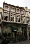 Huis met lijstgevel, voorzien van segmentboogvensters in omlijstingen van Naamse steen met van boven getrapte contour.