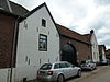 Hoeve met binnenplaats, grotendeels van baksteen en met puntgevel van mergel; op poort sluitsteen