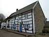 Hoeve van vakwerk onder een zadeldak met het nr 1. Topgevel van breuksteen. Bakhuis