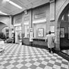 Interieur overzicht stationshal, met voormalig loket, nu kiosk. Ook te zien- tegeltableaux boven de lokketten. - Weert - 20326117 - RCE -  N.S. Station: Interieur overzicht stationshal, met voormalig loket, nu kiosk. Ook te zien: tegeltableaux boven de lokketten. 