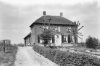 Rietgedekte boerderij, voordeur in het midden van de voorgevel, vensters met roedenverdeling en luiken, erfbeplanting, leibomen