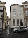 Huis met gebosseerd geelgepleisterde lijstgevel en schilddak, op de hoek van de morgenstraat