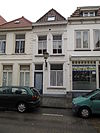 Huis met eenvoudige geelgepleisterde lijstgevel en schilddak