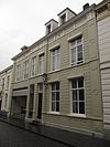 Huis met gebosseerd grijsgepleisterde lijstgevel uit plm 1850, zadeldak