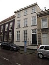 Huis met gebosseerd gepleisterde lijstgevel en trap met bordes voor de ingang