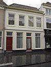 Huis met witgeverfde lijstgevel en zadeldak met rode pannen