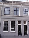 Huis met gebosseerd gepleisterde gevel met kroonlijst op consoles die voortzetting is van die van nr 64