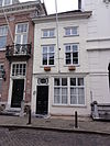 Huis met eenvoudige witgeschilderde lijstgevel met schuiframen
