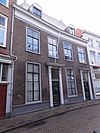 Huis met fraaie gevel uit het begin van de 19e eeuw, met twee ingangen omlijst door geblokte pilasters en kroonlijsten op voluutvormige consoles en mooie deuren met amandelvormige kussenpanelen