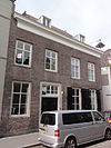 Huis met eenvoudige gevel uit begin 19e eeuw, waarachter een ouder zeer diep pand, reikend tot aan de dieze waar twee topgevels