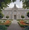 Voorgevel middenvleugel, ingangspartij met erboven een beeld van Sint Joseph met kind in nis en gedeelte van de voortuin - Dongen - 20336951 - RCE -  Klooster Franciscanessen: Voorgevel middenvleugel, ingangspartij met erboven een beeld van Sint Joseph met kind in nis en gedeelte van de voortuin 