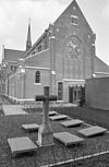 Exterieur westgevel van de driebeukige kruiskerk met vieringtoren en gedeelte van de begraafplaats - Dongen - 20324688 - RCE -  Klooster Franciscanessen: Exterieur westgevel van de driebeukige kruiskerk met vieringtoren en gedeelte van de begraafplaats 