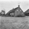Overzicht van rietgedekte boerderij, weg met anwb handwijzer op de voorgrond