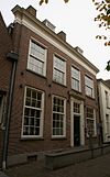 Huis onder dwars, door schoorstenen bekroond, schilddak en met lijstgevel in lodewijk