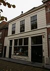 Huis onder schilddak en met gebosseerd gepleisterde lijstgevel waarin boven zesdelige schuiframen