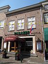 Huis met schilddak en witgepleisterde lijstgevel. Nog geheel woonhuisvorm