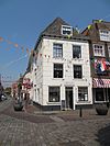 Huis met schilddak en gebosseerd witgepleisterde lijstgevel