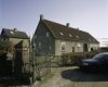 Overzicht van de zuidwestgevel van de boerderij met hekpijler en hek op de voorgrond