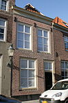 Huis onder schilddak en met lijstgevel, boven met zesdelige schuiframen. Met eigen stoep