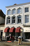 Heusden - Botermarkt 21 - 't Heusdens IJshuys.JPG -  Omvat twee huizen; het linkse onder schilddak met rode pannen en met gepleisterde lijstgevel waarin vensters met kuiven in stucwerk, XIXc; het rechtse onder hoog schilddak en met lijstgevel waarin segmentvormig overtoogde vensters; een stoeppaal. Het dak vormt een geheel met dat van Nieuwstraat 14. 