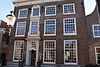 Heusden - Wijksestraat 38 (- Woonhuis.JPG -  Deze woning kent verschillende bouwfasen. De kelders zijn van rond 1400. Het uiterlijk van dit pand is vaak aangepast. De huidige bouwstijl dateert uit de 18e eeuw. Huis met hoge gevel waarop rechte kroonlijst op gesneden consoles; versierde deurtravee met alliantiewapen in top. 
