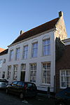 Heusden - Waterpoort 7 - Herenhuis.JPG -  Herenhuis van vijf traveeÃ«n, met gecementeerde lijstgevel; ontlastende korfbogen boven de vensters; zesdelige schuiframen. Dwars zadeldak tussen zijtopgevels. Zes stoeppalen met zwarte ruitpatronen. 