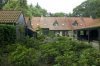 Zicht op een gedeelte van de achtergevel van de voormalige boerderij, bijgebouwen op de voorgrond