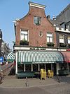 Hoekhuis met gevel onder klokvormige top met rollagen en afdeklijst