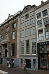 Pand met zandstenen gevel met geblokte hoeklisenen en met beeldhouwwerk gevulde halfcirkelvormige bekroning