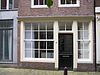 Huis met latere gepleisterde gevel bekroond door een 19e-eeuwse klokvormige top met rollagen