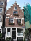 Huisje met gepleisterde puntgevel waarin 4 lelieankers