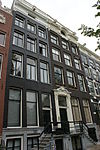 Pand met gevel onder rijk gebeeldhouwde verhoogde zandstenen lijst en attiek met gesneden deuromlijsting uit de bouwtijd en uitwendig in empirestijl gewijzigde deur