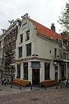 Hoekhuis met gepleisterde gevel onder uit en ingezwenkte top met rollagen