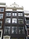 Pand met gevel onder gesneden lijst met ingezwenkte verhoging. Gesneden deuromlijsting