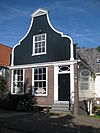 Houten dijkhuis met klokgevel (uit- en ingezwenkt voorschot) uit 19de eeuw en met bakstenen onderpui