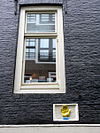 Dubbel pakhuis met trapeziumgevels aan voor- en achterzijde beide met gevelsteen met hand, bij de laatste met een grote kroon erboven