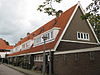 Blok met 8 keukenwoningen, zo genoemd vanwege destijds nieuwe plaatsing van keuken aan de voorzijde, aan de zijkant een houten topgevel, bouwstijl Amsterdamse School, samen met de poortgebouw langs de Purmerweg centraal deel van Tuindorp Nieuwendam